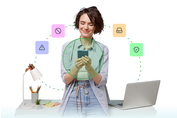 A woman is standing in front of a desk with a lamp, pencil case, laptop, small plant, and far too many Post-It notes. She is smiling and looking at something on her phone, which is highlighted with a green circle.